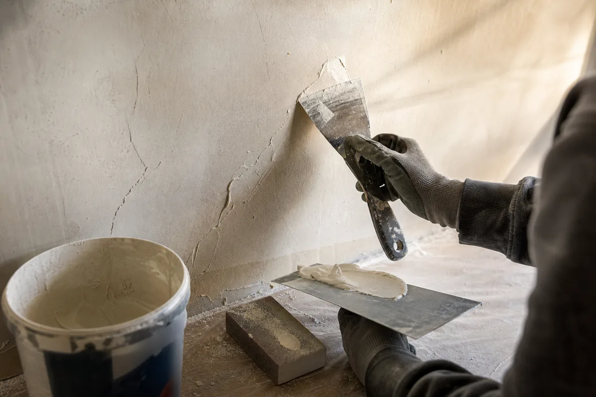 Artisan peintre appliquant une peinture claire au rouleau sur un mur intérieur à Montpellier